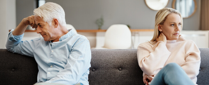 Middle-aged couple sitting away from each other on a couch