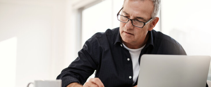 Older man reviewing documents on a laptop