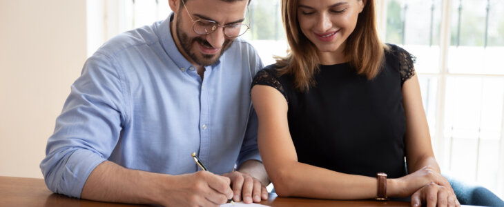 Couple smiling while signing a joint document