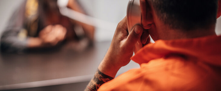 View from over the shoulder of a male prisoner speaking with a female visitor