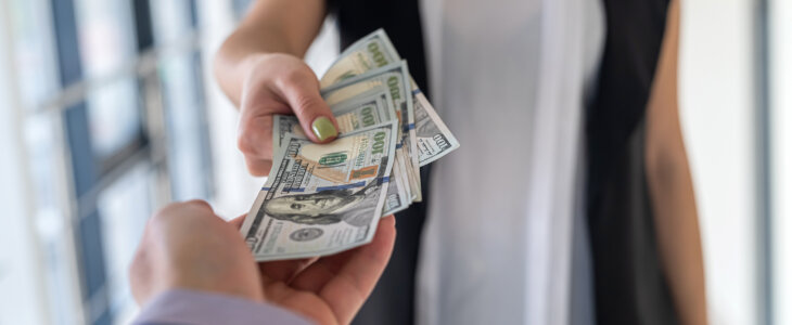 Man and woman exchanging a stack of hundred dollar bills