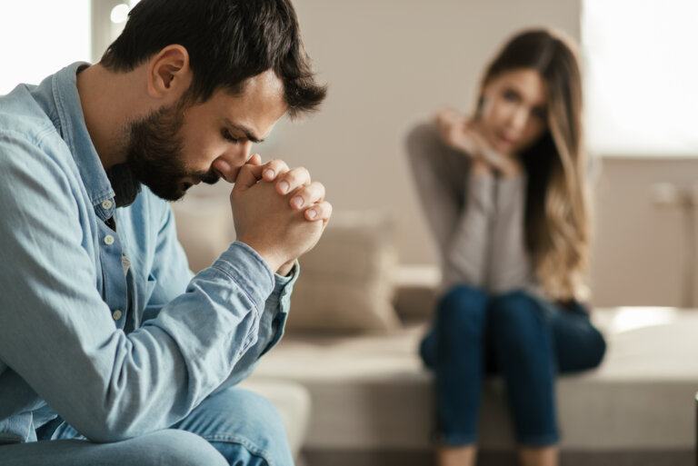 oung man feeling sad after arguing with his girlfriend on sofa at home.