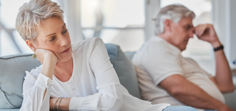 White senior couple sitting on opposite ends of the couch