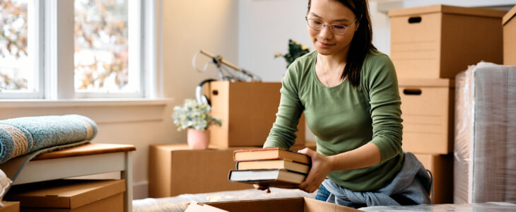 Young Asian woman packing her belongings in cardboard boxes