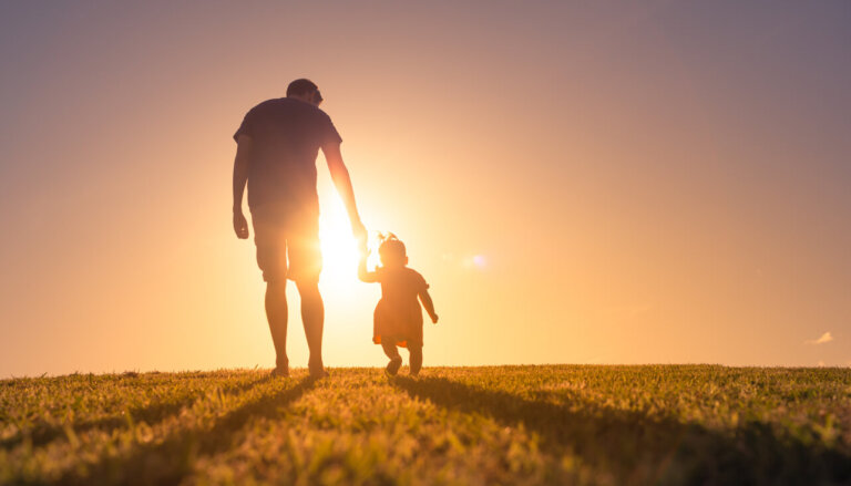 Father and daughter walking at sunset outdoors.